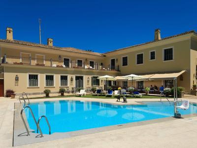 Duży hotel z basenem na zewnątrz i parasolami przeciw słoncu pod czystym niebieskim niebem.