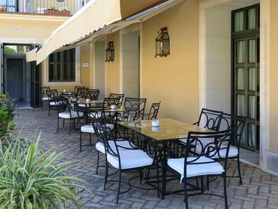 Elegancki taras z czarnymi metalowymi stołami i białymi tapicerowanymi krzesłami przy hotelu.