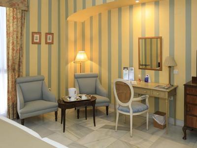 Przytulny kącik z dwoma fotelami, stolikiem i biurkiem w pokoju hotelowym.