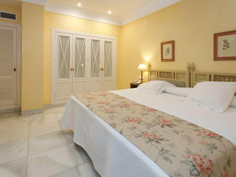 Schlafzimmer mit zwei Einzelbetten, gelben Wänden, weißen Schränken und Marmorfußboden.