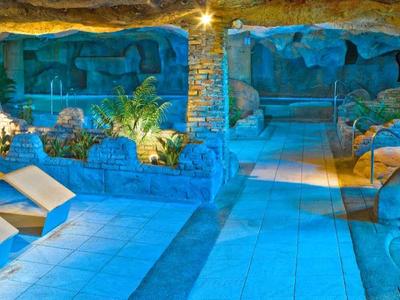 Piscina esterna riscaldata con comodi lettini e ambiente roccioso naturale al tramonto