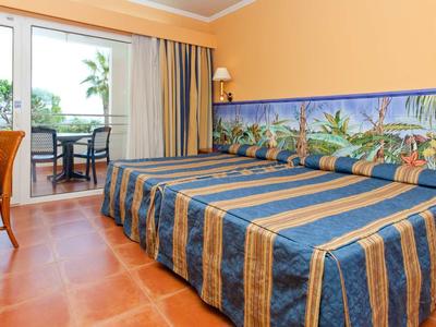 Camera d'hotel con due letti singoli, terrazza e vista su palme