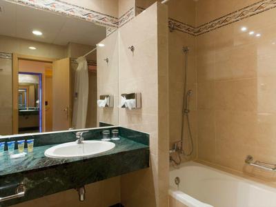 Bagno luminoso con lavabo, vasca da bagno e specchio.