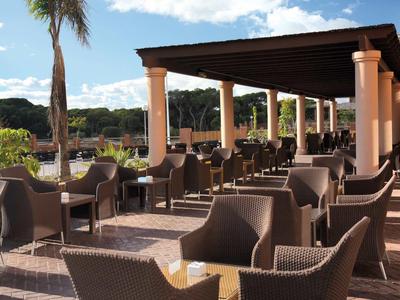 Taras z krzesłami i stołami pod zadaszeniem z widokiem na zielone wzgórza