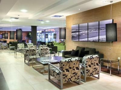 Nowoczesna lobby hotelowa z wzorzystymi fotelami, kanapami i dużymi obrazami na ścianie w tle.