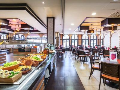 Jasna restauracja hotelowa z bufetem i nakrytymi stołami w nowoczesnym otoczeniu.