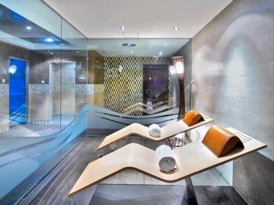 Moderner Wellnessraum mit Liegen, Glaswand und atmosphärischer indirekter Beleuchtung.