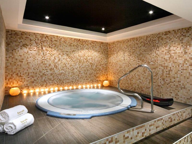 Moderner Wellnessbereich mit rundem Whirlpool, marmorierter Wand und warmem Licht.