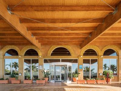 Vstupní prostor hotelu s dřevěným stropem a velkými okny s výhledem na rostliny