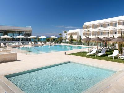 Espace piscine moderne d'hôtel avec chaises longues et parasols sous un ciel bleu.