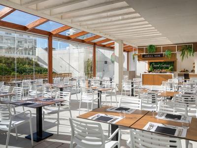 Restaurant lumineux et moderne avec chaises blanches sous un toit en verre près de l'hôtel.