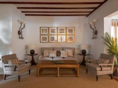 Elegancki salon z sofą, fotelami, drewnianym stołem i roślinami pod drewnianym stropem z belkami.