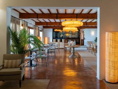 Nowoczesna przestrzeń lobby hotelu z krzesłami, stołami i ciepłym oświetleniem.