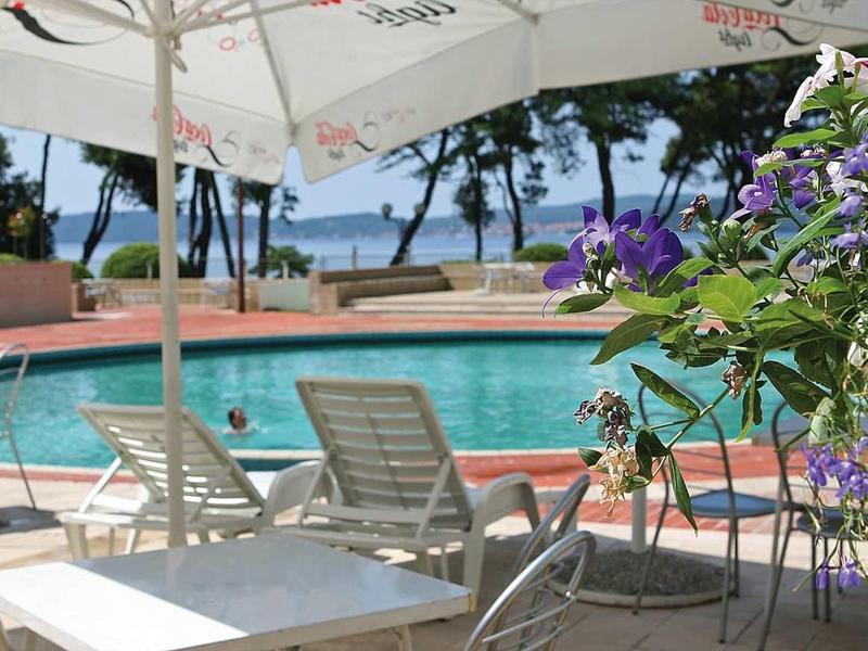 Area piscina con sedie, tavoli e ombrelloni accanto a fiori in fiore