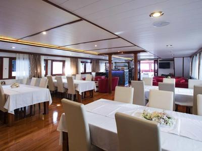 Wnętrze nowoczesnej restauracji hotelowej z białymi obrusami i krzesłami.