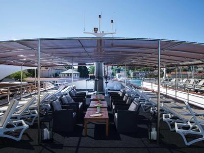 Terrazza solarium con lettini e tavoli sotto un tetto di vetro su una nave.