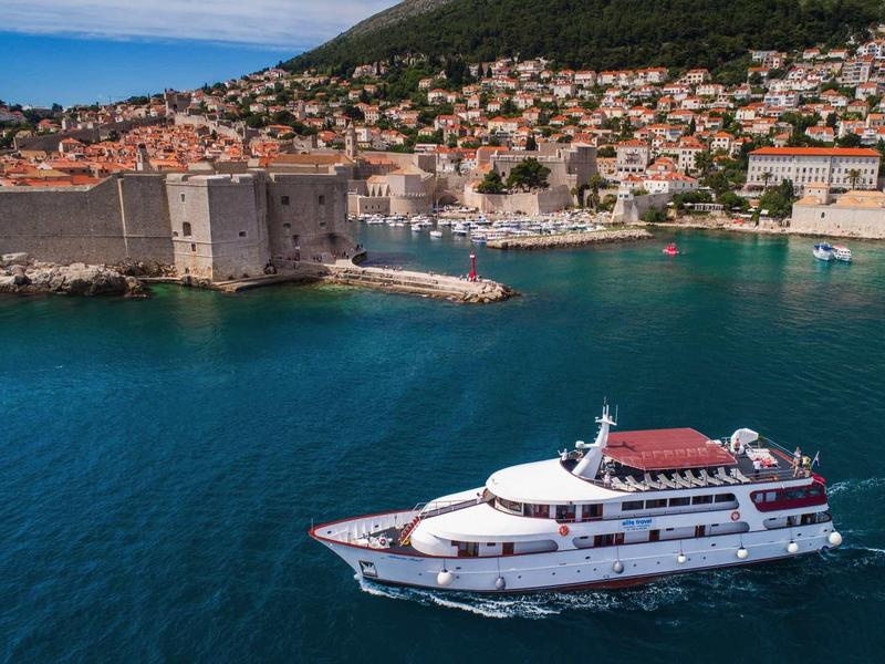Lussuosa nave da crociera vicino a città costiera storica con acqua azzurra limpida.