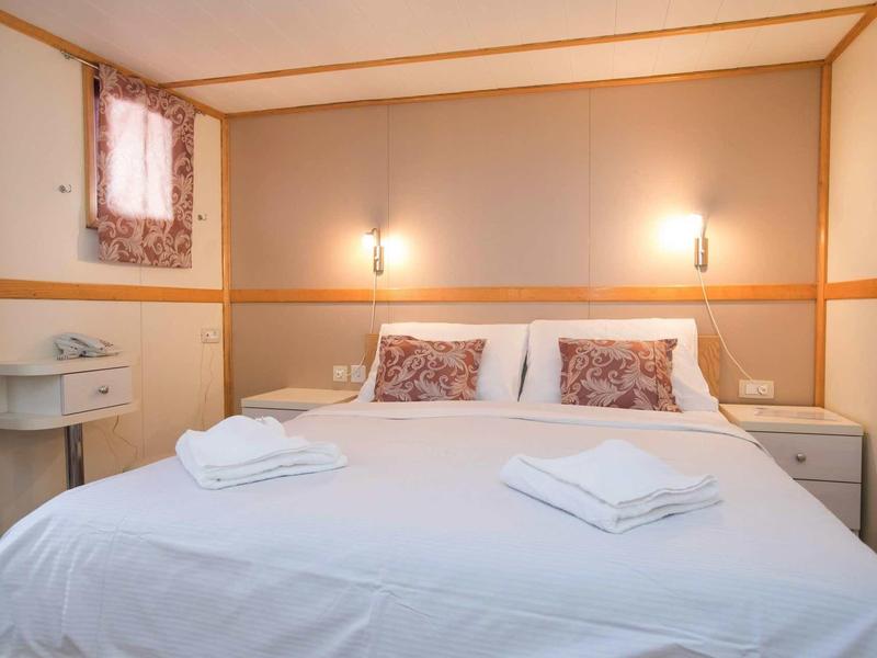 Camera d'hotel accogliente con letto matrimoniale, biancheria bianca e comodini.