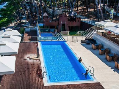 Piscina con acqua limpida e ombrelloni bianchi su terrazza vicino all'acqua