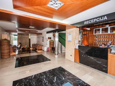 Hotel reception with brown wood panels, black counter, and seating area with sofas
