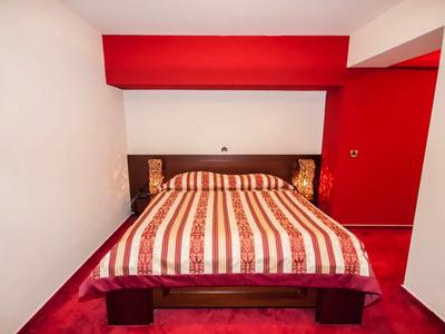 Bedroom with double bed, striped bedding, and red walls.