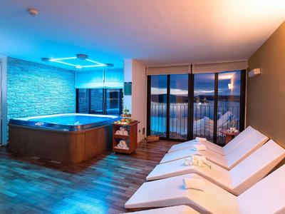 Relaxation area with hot tub, lounge chairs, and large window with outdoor view.