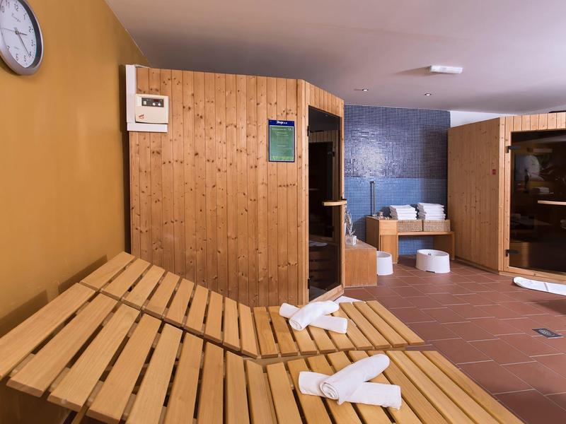 Sauna area with wooden loungers, towels, and a wooden sauna in a relaxation room.