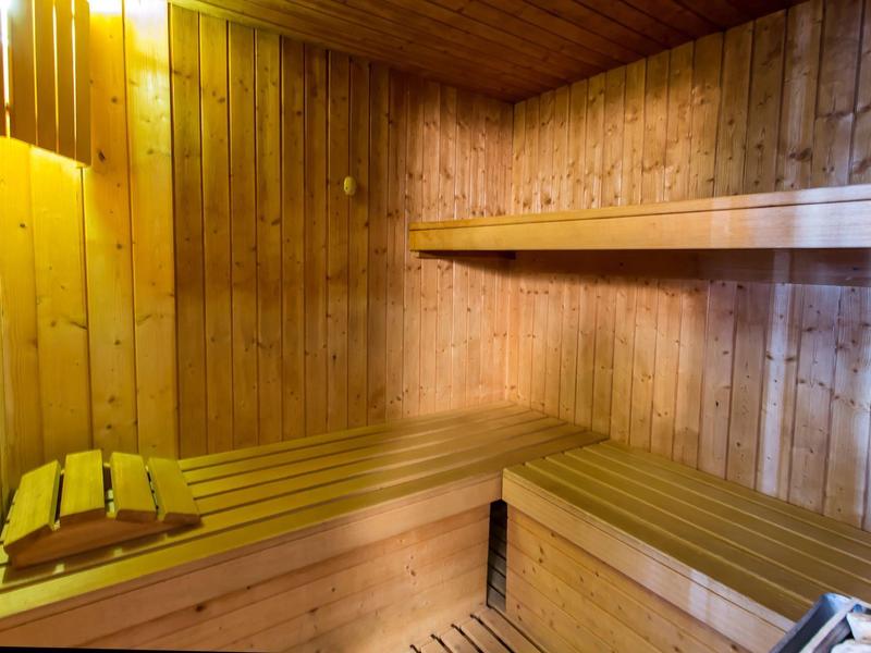 Interior of a sauna with wooden benches and walls in warm lighting.