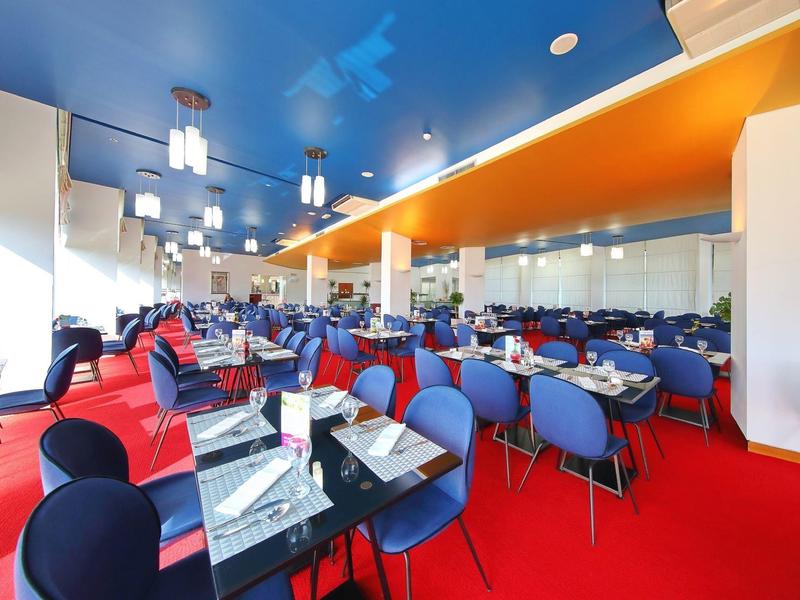 Large dining room with colorful chairs, red carpet, and blue ceiling.