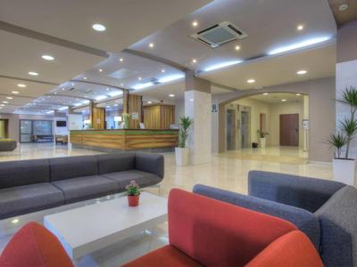 Hall d'hôtel moderne avec zones d'assise, sols clairs et éclairage subtil.