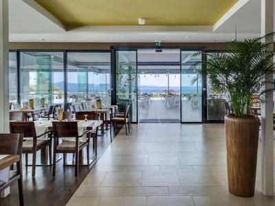 Espace lumineux du restaurant de l'hôtel avec tables, chaises et vue sur une terrasse et un paysage aquatique.