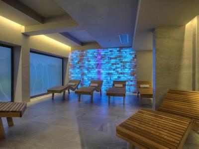 Espace lounge avec mobilier en bois rayé et mur en pierre éclairé en bleu.