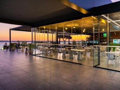 Terrasse d'hôtel moderne avec chaises et tables au coucher du soleil avec vue sur la mer.