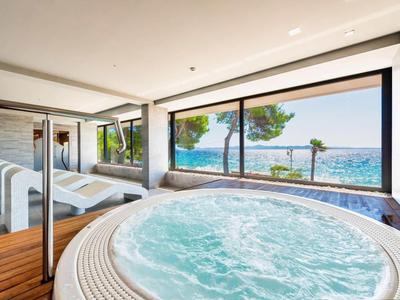 Jacuzzi intérieur avec vue sur la mer et chaises longues dans une salle de bien-être moderne.