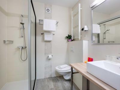 Salle de bain moderne avec douche, toilettes et lavabo aux tons neutres.
