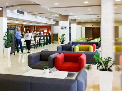 Hall d'hôtel moderne avec des espaces assis colorés et un bar en arrière-plan.