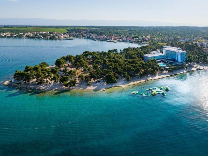 Littoral avec hôtels, forêts et plages sur une mer bleue calme sous un ciel clair.
