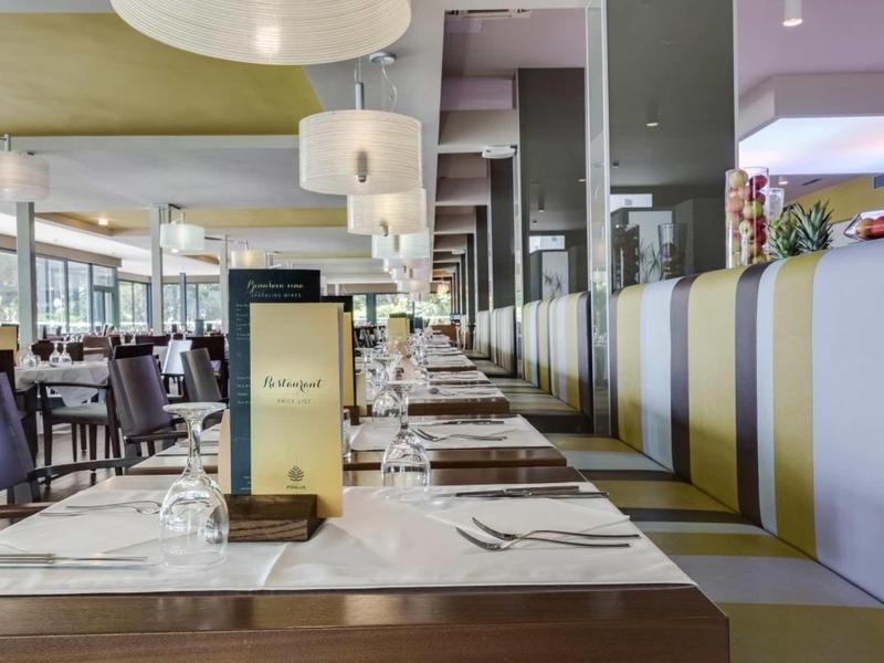 Salle de restaurant d'hôtel moderne avec longues tables et banquettes élégantes.