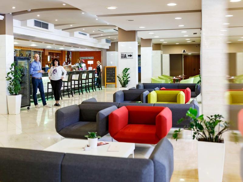 Hall d'hôtel moderne avec des espaces assis colorés et un bar en arrière-plan.