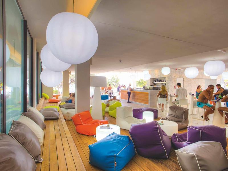 Salon moderne avec poufs colorés et grandes lampes rondes dans un café ou espace hôtelier.
