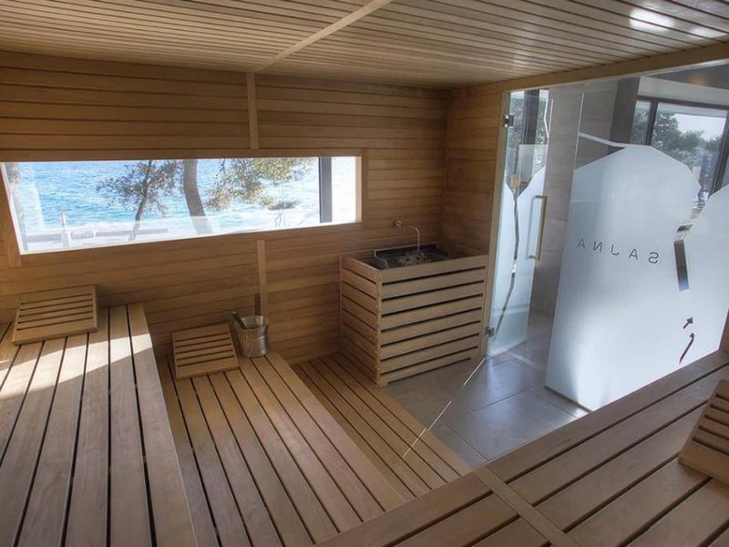 Intérieur de sauna lumineux avec grandes fenêtres et bancs en bois donnant sur un paysage enneigé.