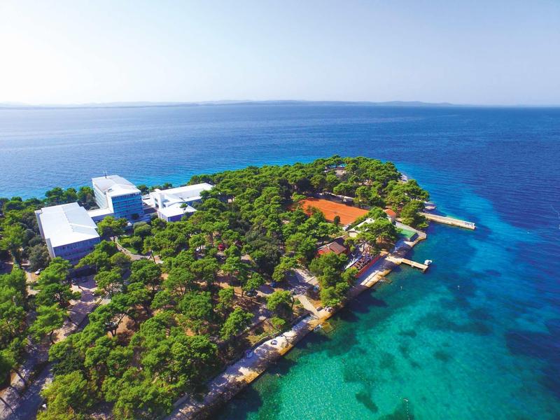 Vue aérienne d'une île boisée avec des bâtiments et une eau turquoise claire
