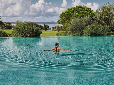 Personne nageant dans une piscine à débordement avec vue sur le paysage et le ciel.