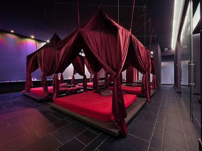 Wnętrze z ciemnoczerwonymi, wyściełanymi miejscami do siedzenia pod tkaninowymi daszkami w nowoczesnym otoczeniu.