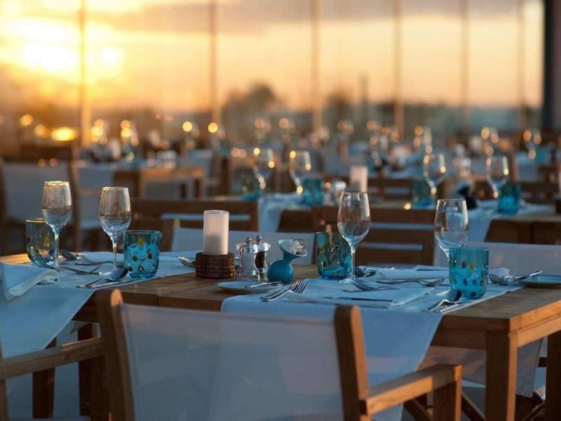 Elegancka restauracja z zastawionymi stołami i szkłem o zachodzie słońca.