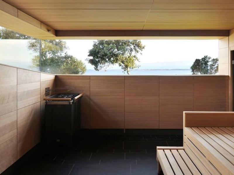 Pokój sauny z drewnianymi ławkami i widokiem na drzewa i morze