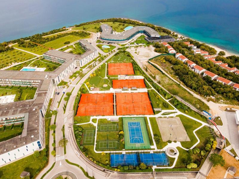 Widok z lotu ptaka na kompleks hotelowy z kortami do tenisa blisko wybrzeża i morza.