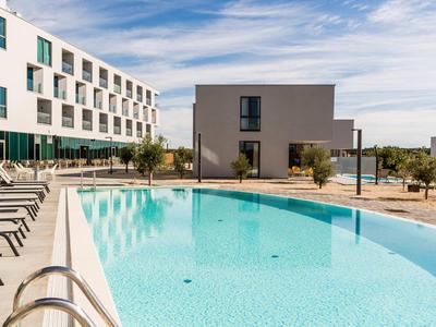 Piscina moderna dell'hotel con lettini e acqua chiara e blu in una giornata di sole.