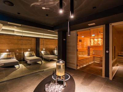 Moderne wellnessruimte met ligstoelen en sauna in warme kleuren.