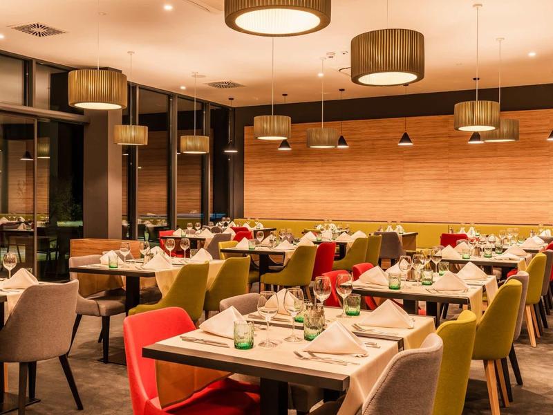 Modern restaurant met kleurrijke stoelen en elegant gedekte tafels in warm licht.